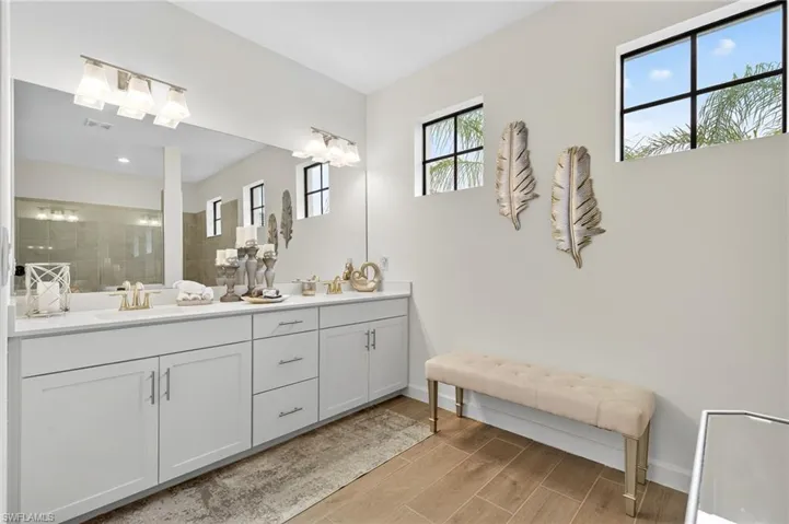 Bathroom featuring double vanity, wood finished floors, and tiled shower