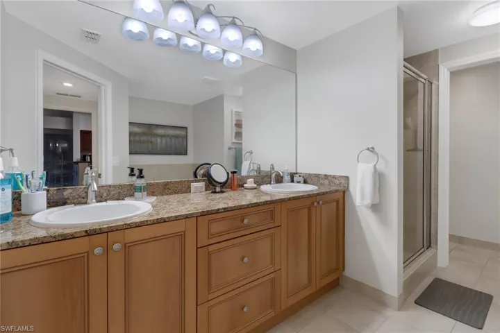 Bathroom featuring tile patterned flooring, a shower with door, and vanity