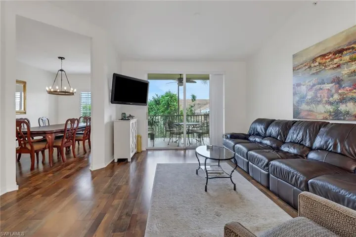 Living room with plenty of natural light, dark hardwood / wood-style floors, and a notable chandelier