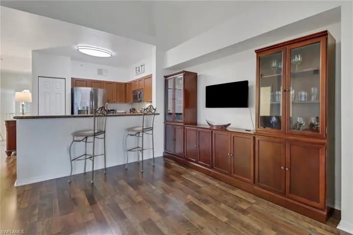 Kitchen with dark stone countertops, a kitchen breakfast bar, kitchen peninsula, dark hardwood / wood-style floors, and appliances with stainless steel finishes