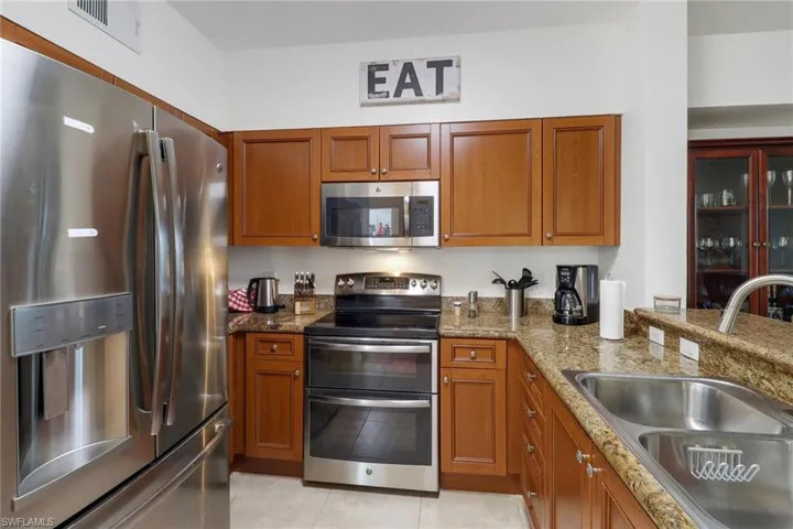 Kitchen featuring light stone counters, stainless steel appliances, light tile patterned flooring, and sink