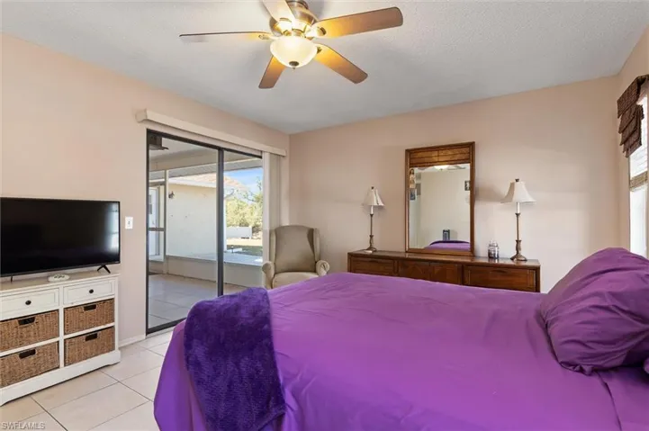 Bedroom with access to outside, a ceiling fan, light tile patterned flooring, and a textured ceiling