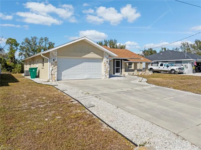 View of front facade with stone siding, concrete driveway, a front yard, and an attached garage