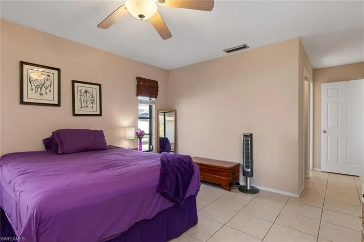 Bedroom with ceiling fan, light tile patterned flooring, and a textured ceiling