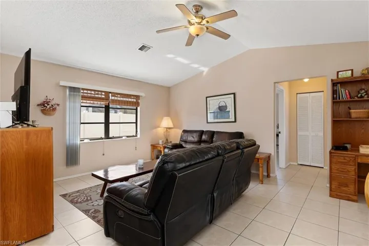 Living room with light tile patterned flooring, vaulted ceiling, and ceiling fan