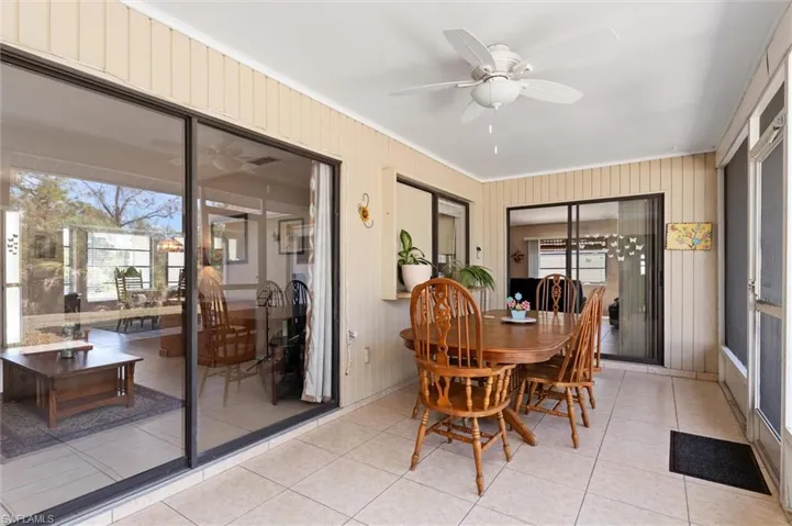 Dining room featuring ornamental molding, ceiling fan, light tile patterned floors, and wood walls