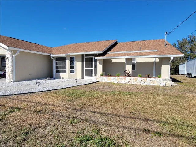 View of front of house featuring stucco siding, a front lawn, and roof with shingles