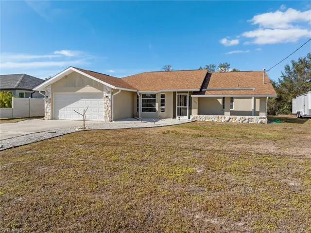 Ranch-style home featuring driveway, a front lawn, an attached garage, and a shingled roof
