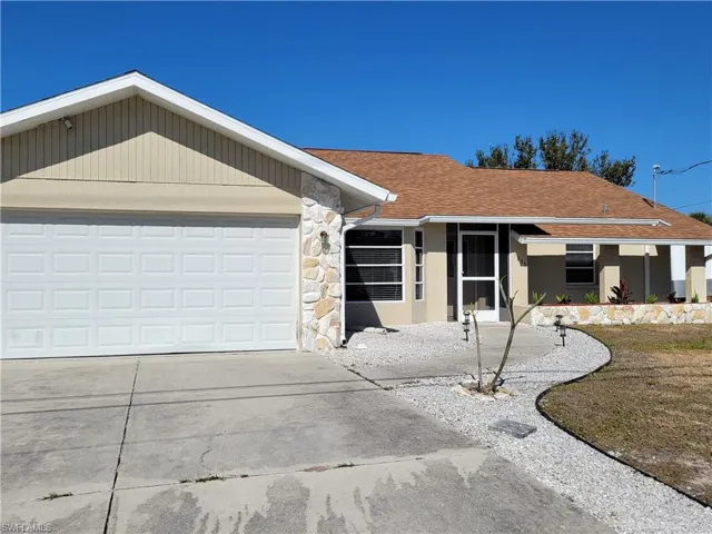 Single story home with stone siding, driveway, a shingled roof, and a garage