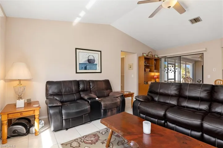 Living room with lofted ceiling, a ceiling fan, and light tile patterned flooring