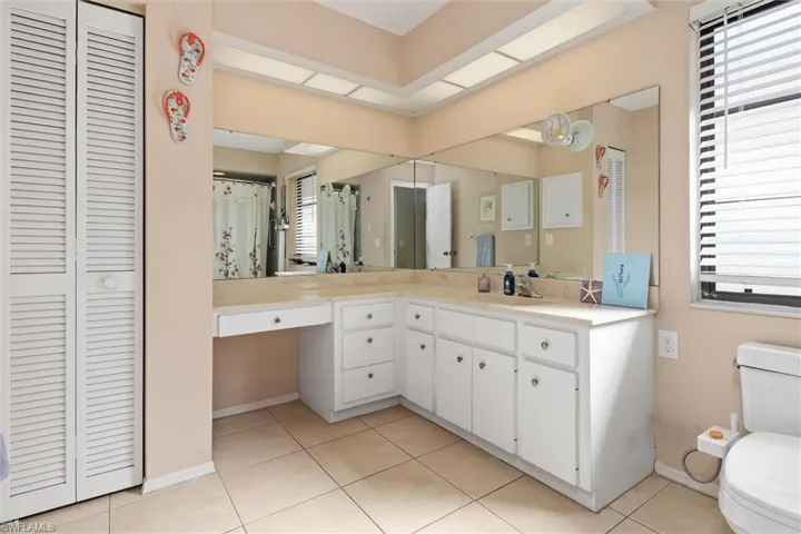 Bathroom featuring a closet, vanity, light tile patterned flooring, and a shower with shower curtain