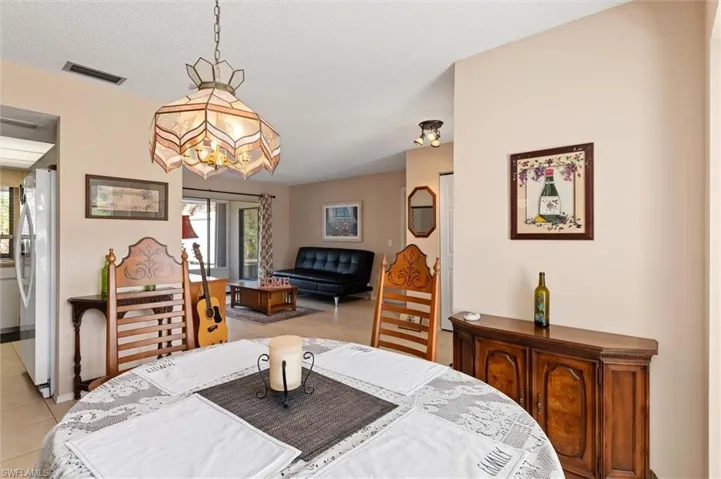 Dining room with light tile patterned flooring, a textured ceiling, and a chandelier
