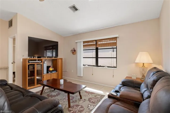 Tiled living area featuring baseboards and vaulted ceiling