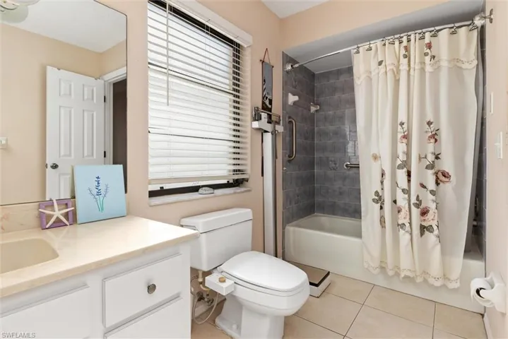 Bathroom with shower / tub combo with curtain, vanity, and light tile patterned floors