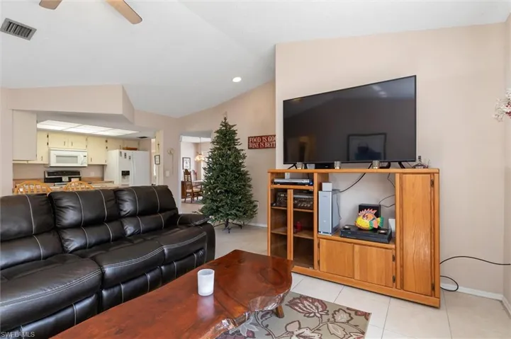 Living room with light tile patterned floors, lofted ceiling, ceiling fan, and recessed lighting
