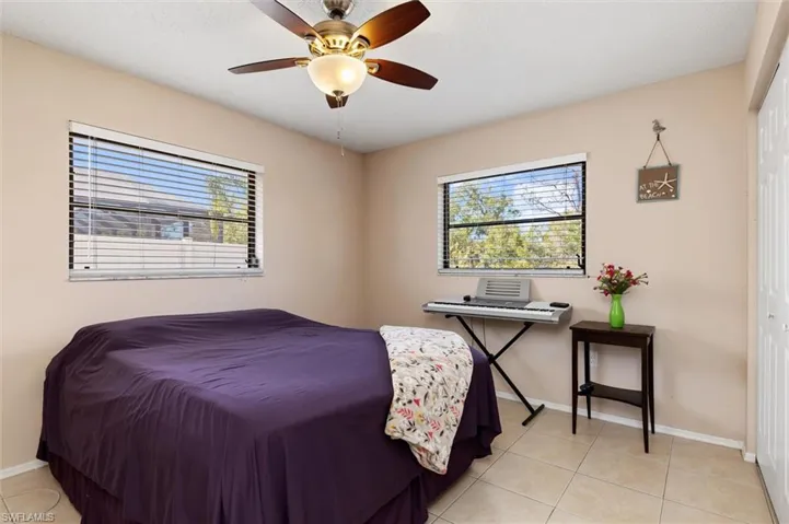 Bedroom featuring ceiling fan, a closet, light tile patterned floors, and multiple windows