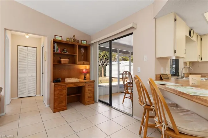 Kitchen featuring open shelves, lofted ceiling, light tile patterned floors, and cream cabinets