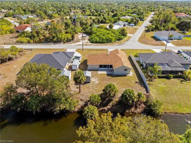 Aerial view of property and surrounding area featuring nearby suburban area and a nearby body of water