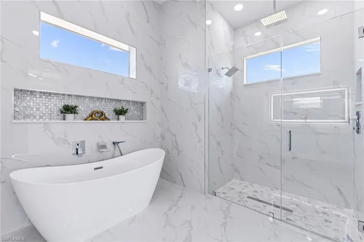 Bathroom featuring independent shower and bath and tile walls