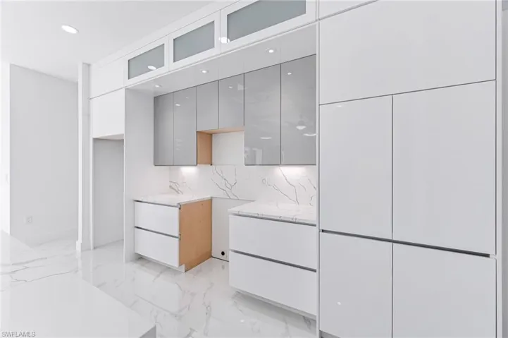 Kitchen featuring backsplash, gray cabinets, and light stone counters