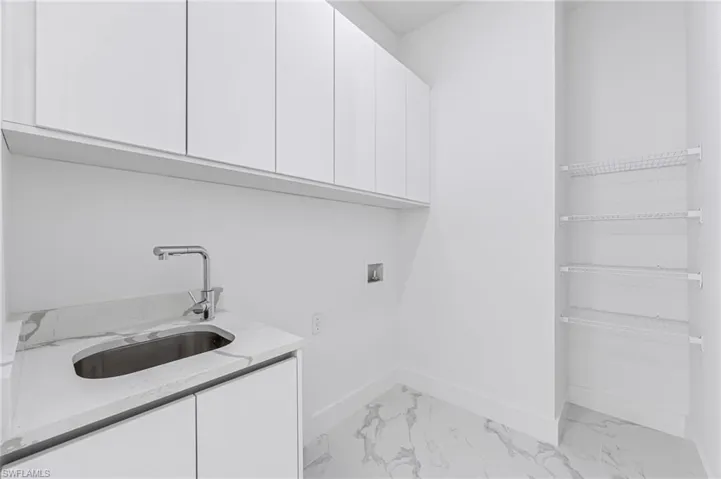 Clothes washing area featuring sink, cabinets, and washer hookup