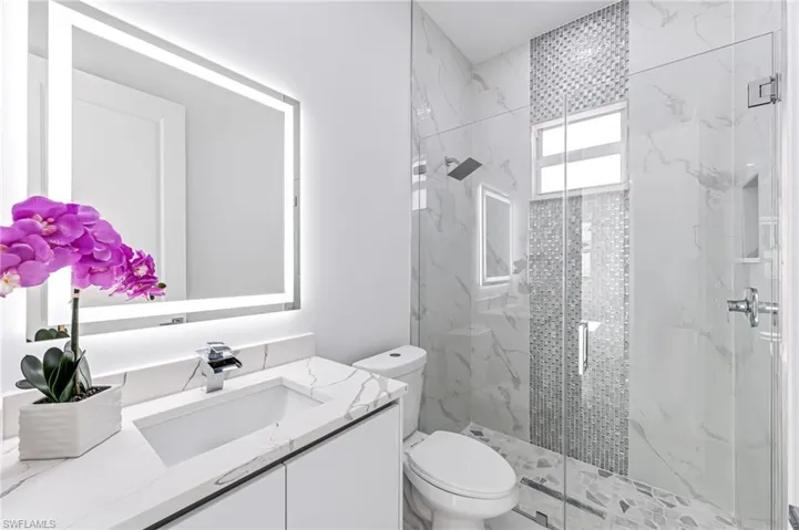 Bathroom featuring a shower with door, vanity, and toilet