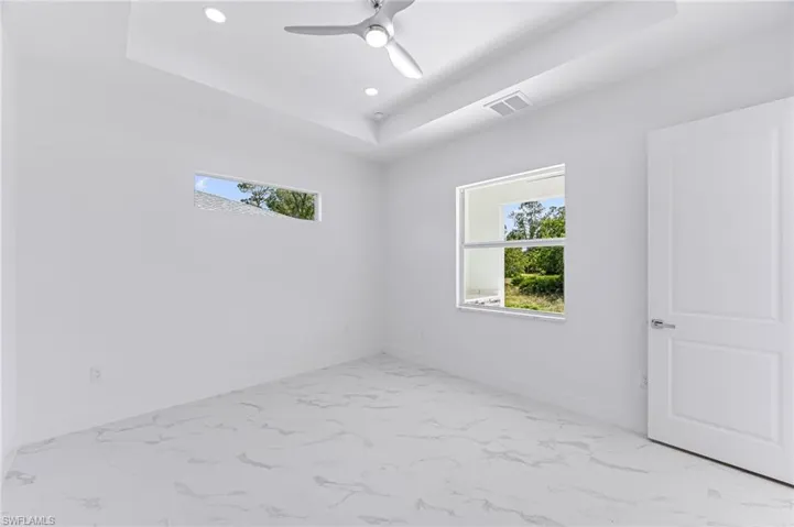Spare room featuring a raised ceiling and ceiling fan