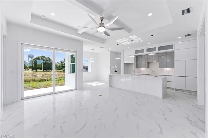 Unfurnished living room featuring a raised ceiling, ceiling fan, and sink