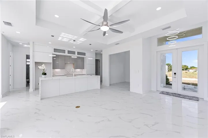 Unfurnished living room with ceiling fan, a raised ceiling, sink, and french doors