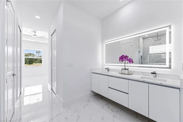 Bathroom with vanity, ceiling fan, and a shower with shower door