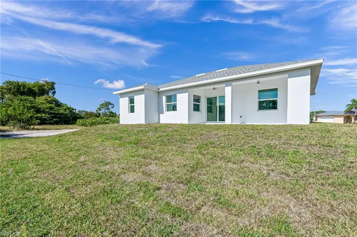 Rear view of property featuring a lawn and ceiling fan
