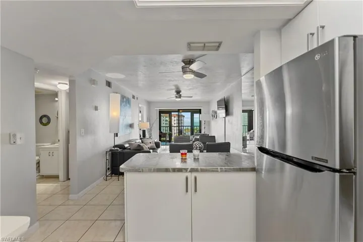 Kitchen featuring freestanding refrigerator, white cabinets, open floor plan, and a peninsula