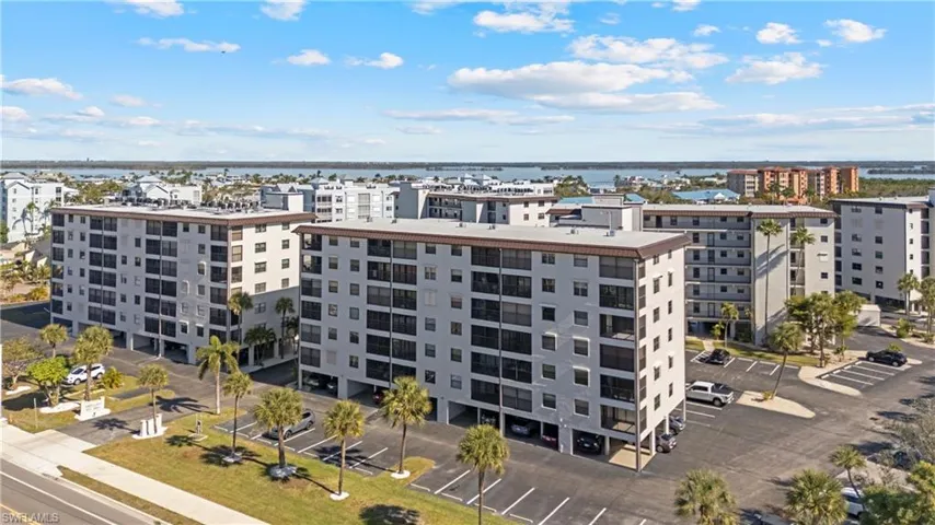 View of apartment building / complex featuring a water view, uncovered parking, and a city view