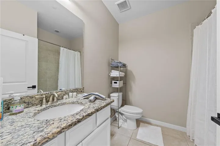 Vanity with a granite-style countertop, undermount sink, and brushed nickel faucet