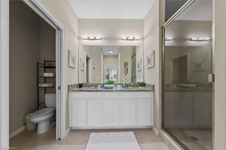 Bathroom featuring a dual vanity with white cabinetry, granite countertops, and two undermount sinks
