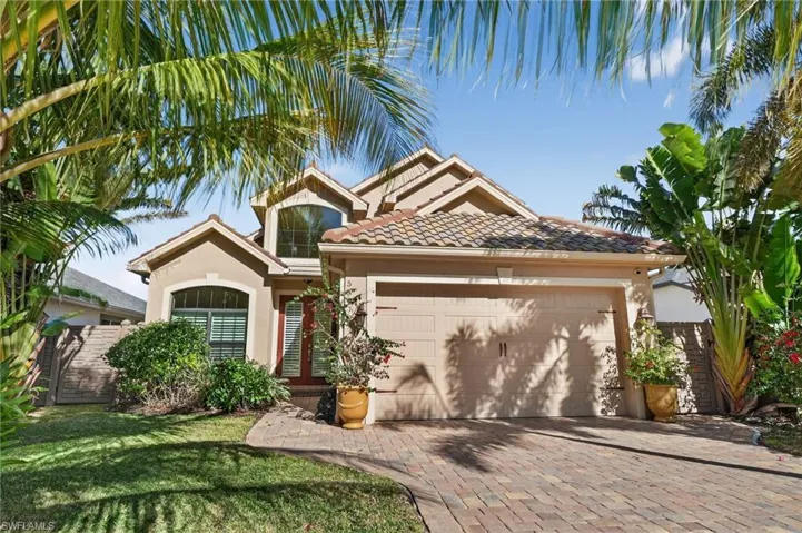 Mediterranean / spanish home featuring a tile roof, stucco siding, a garage, and driveway