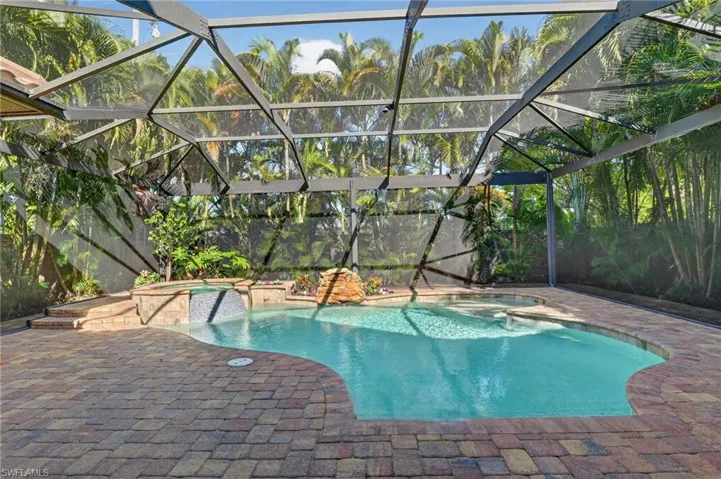 View of pool featuring a pool with connected hot tub, a lanai, a patio, and a sunroom