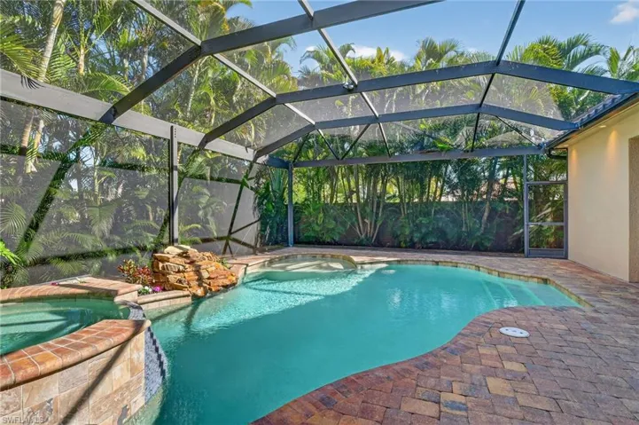 View of swimming pool with enclosure, a pool with connected hot tub, a sunroom, and a patio area