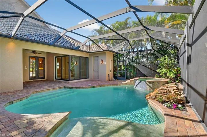 View of swimming pool with a patio, a sunroom, a lanai, a pool with connected hot tub, and french doors