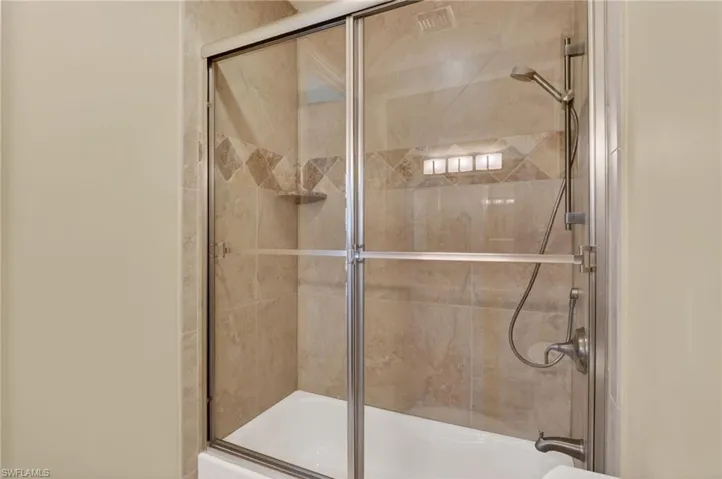 Full bath featuring shower / bath combination with glass door