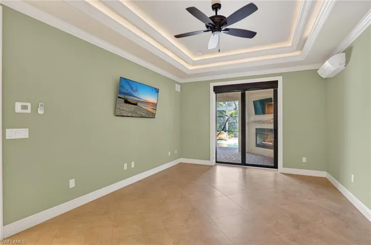 Spare room featuring crown molding, a raised ceiling, a ceiling fan, and a wall mounted air conditioner
