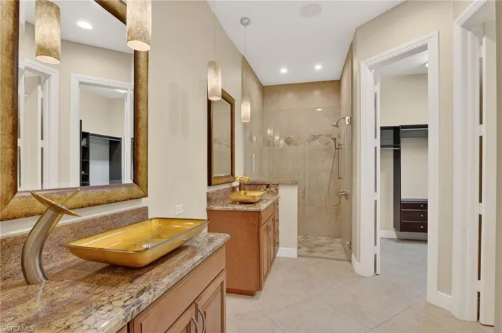 Bathroom featuring a spacious closet, two vanities, a shower stall, light tile patterned floors, and recessed lighting