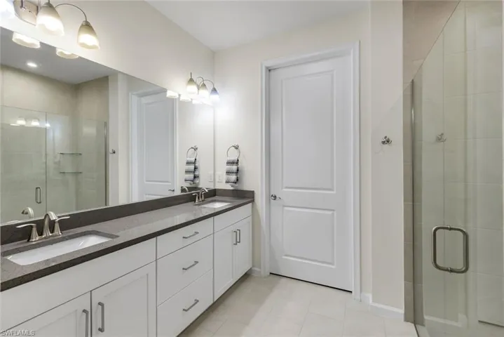 Master bathroom with quartz counters and frameless shower.