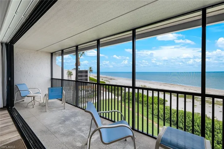 Sunroom / solarium featuring view of water and beach and a balcony