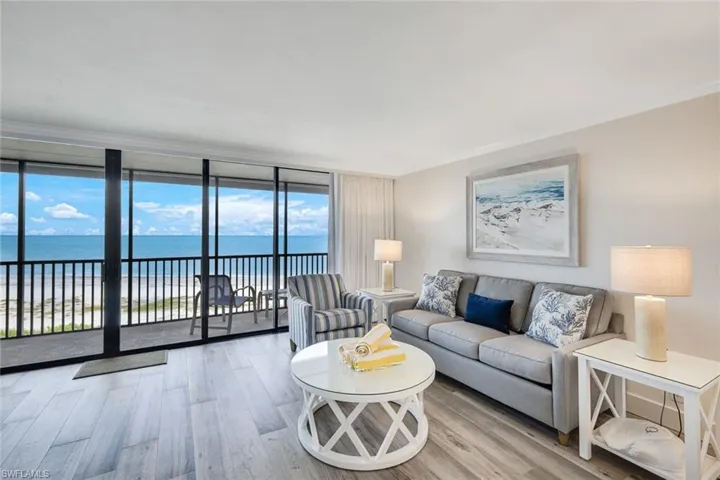 Living area with expansive windows, light wood-style floors, a water view, and crown molding