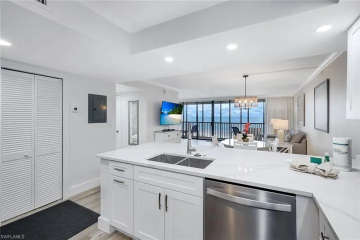 Kitchen featuring white cabinets, dishwasher, crown molding, open floor plan, and hanging lights