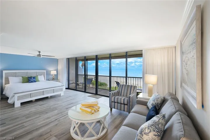 Bedroom with expansive windows, access to exterior, wood finished floors, a water view, and a ceiling fan