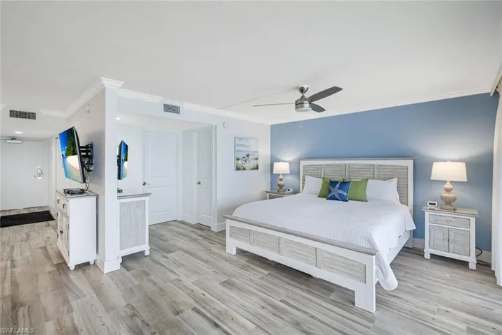 Bedroom with crown molding, light wood-style floors, and ceiling fan
