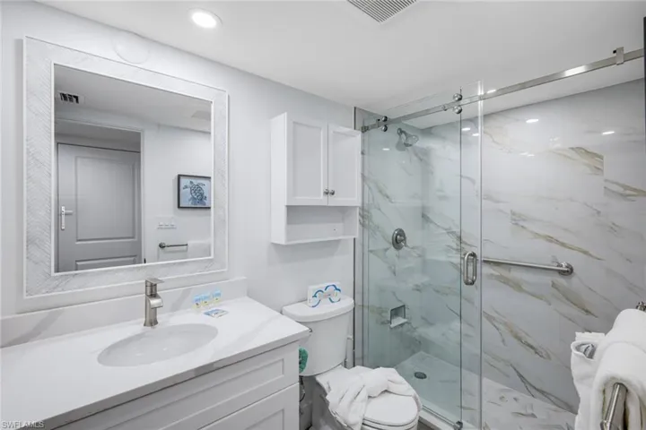 Bathroom featuring a marble finish shower and vanity