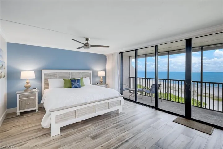 Bedroom with a water view, ornamental molding, access to exterior, light wood-style floors, and expansive windows
